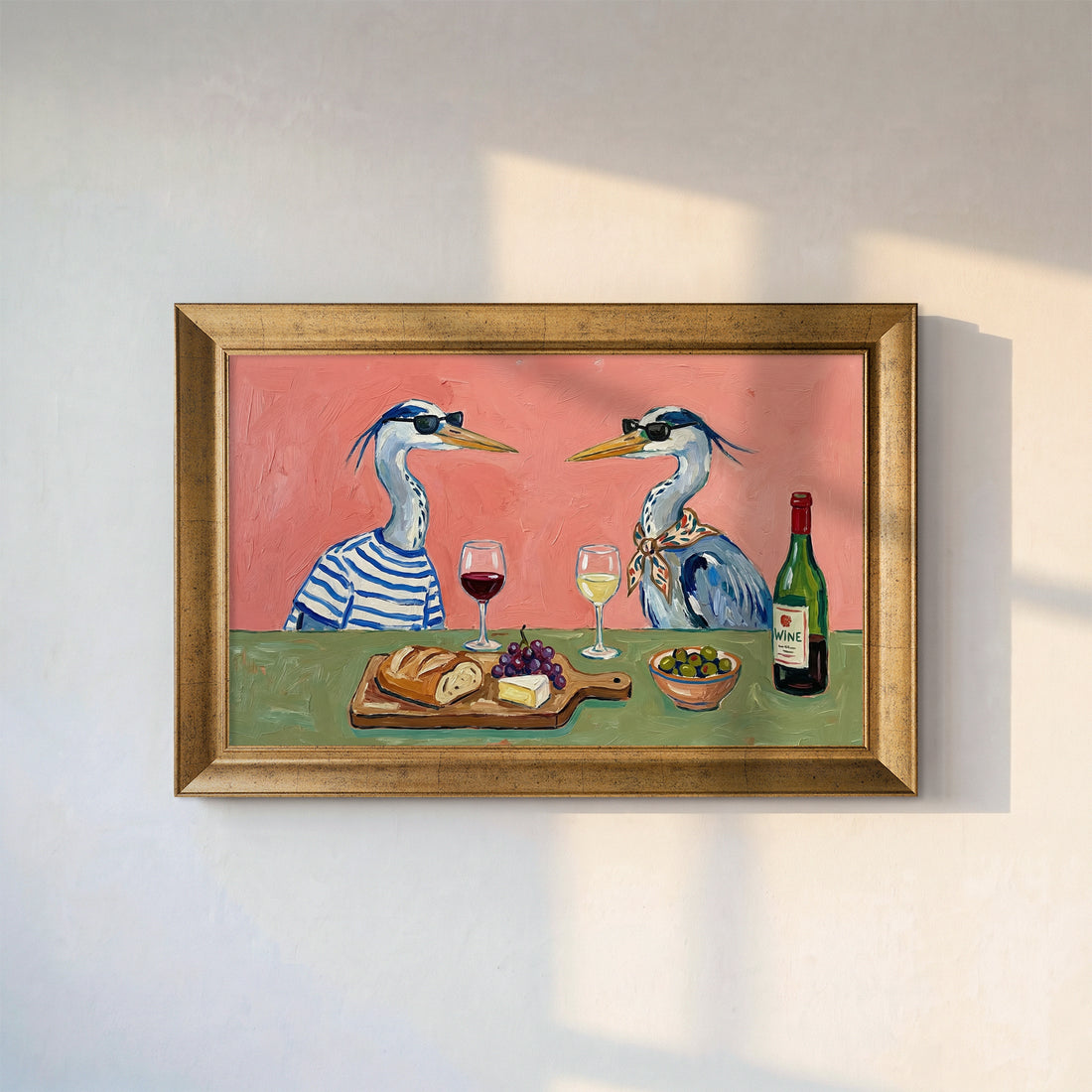 Two herons in sunglasses sharing wine, bread, grapes and cheese at a green table on a pink wall, gold frame