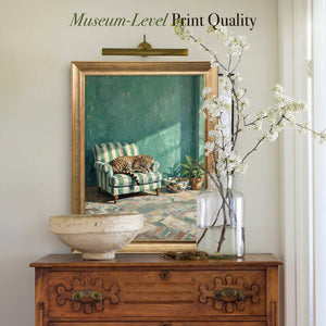 Leopard on Green Striped Armchair canvas print in a gold frame above a wooden chest with white blossom branches