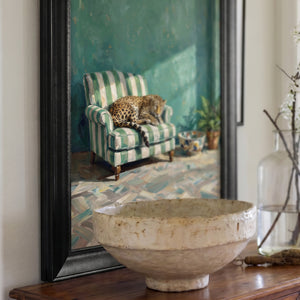 Angled view of the Leopard on Green Striped Armchair canvas print in a black frame above a sideboard with a ceramic bowl