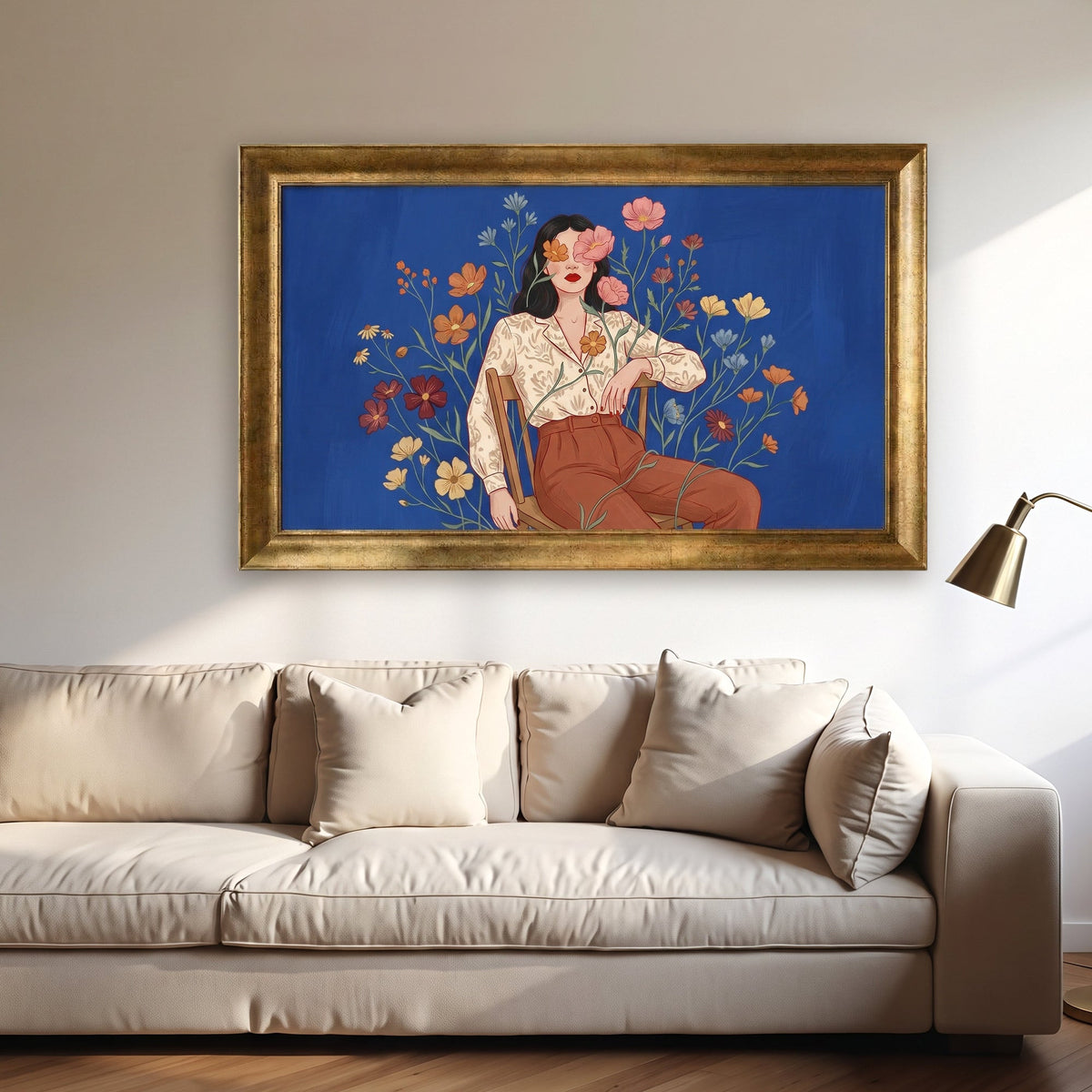 Royal Gold framed canvas print of a seated woman with flowers over her eyes against cobalt blue, above a beige sofa